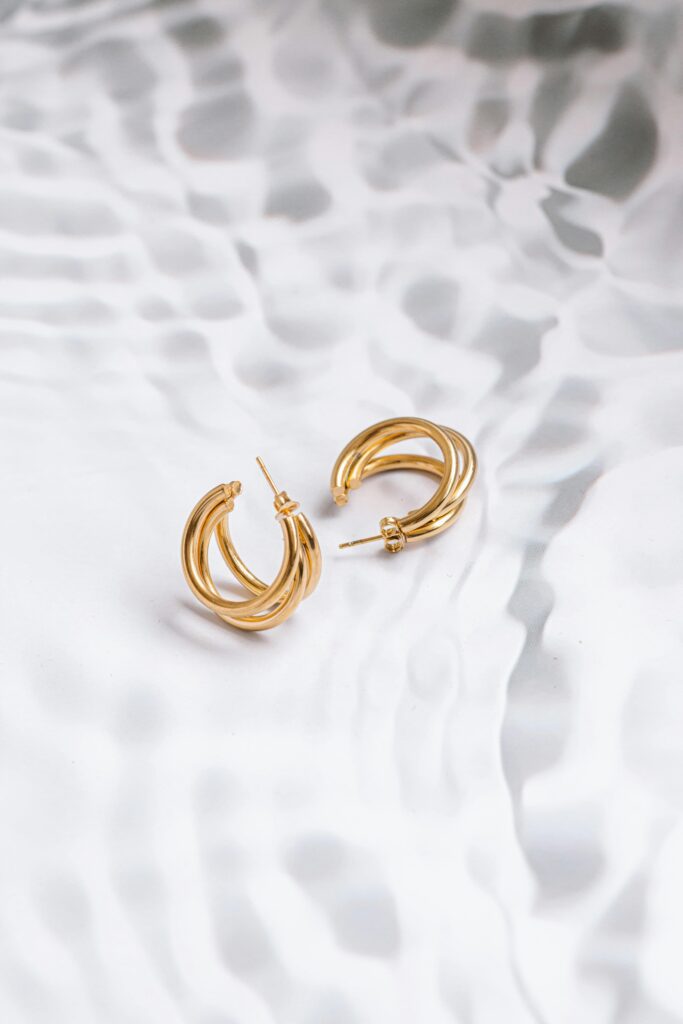 pexels-photo-16935587-16935587 A pair of stylish gold hoop earrings captured on a wavy, textured background, highlighting their elegance.